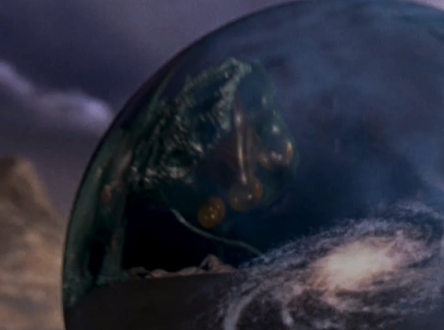 A close up of the Earth marble; a reflection of the alien is seen on the surface